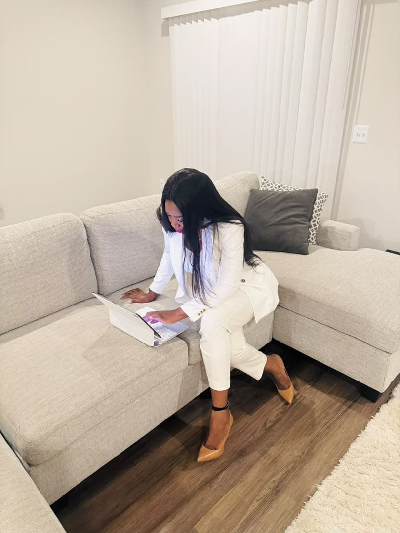 Malorfa in a white suit working on a laptop at home