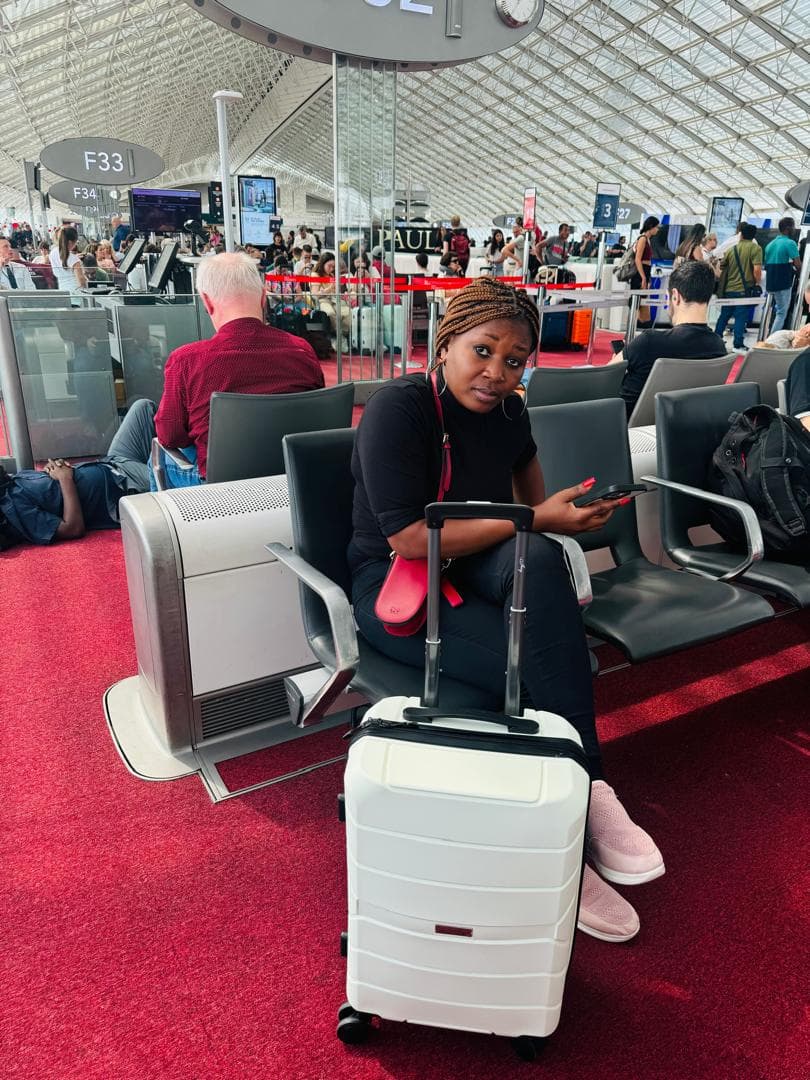 Malorfa at an airport gate with a white suitcase